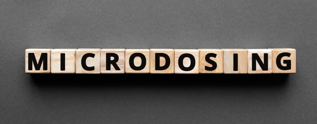 Wooden blocks, each showing an individual letter, spell out the word “microdosing.” 
